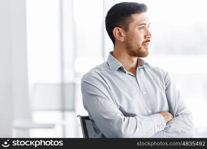 Portrait of businessman. Young businessman standing in offfice with arms crossed