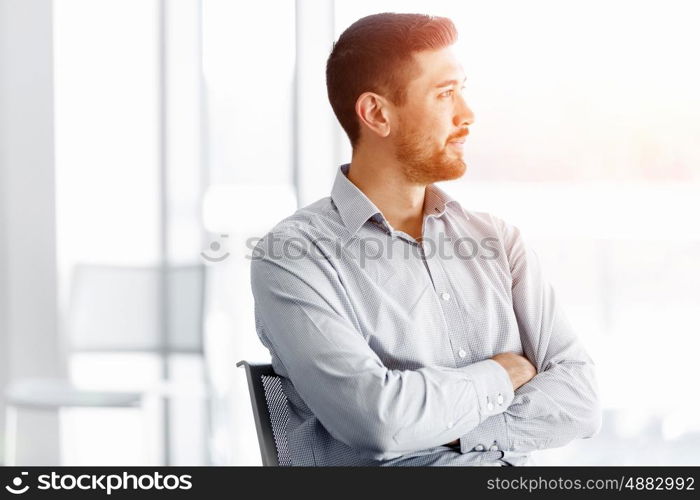 Portrait of businessman. Young businessman standing in offfice with arms crossed