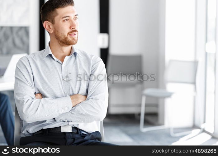 Portrait of businessman. Young businessman standing in offfice with arms crossed