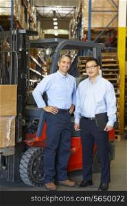 Portrait Of Businessmen With Fork Lift Truck In Warehouse