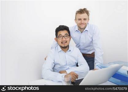 Portrait of businessmen with laptop at desk in office