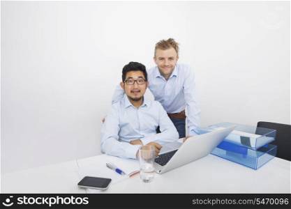 Portrait of businesspeople with laptop at desk in office
