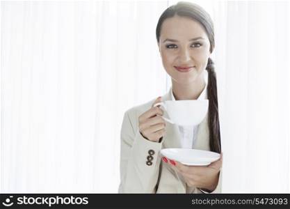 Portrait of businesswoman having coffee in office