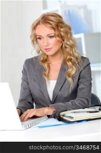 Portrait of businesswoman in office working on laptop computer