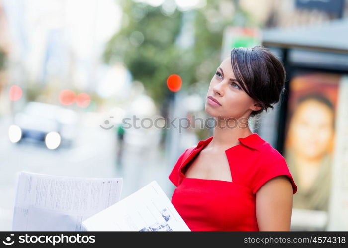 Portrait of businesswoman outside. Portrait of business woman in red dress holding papers