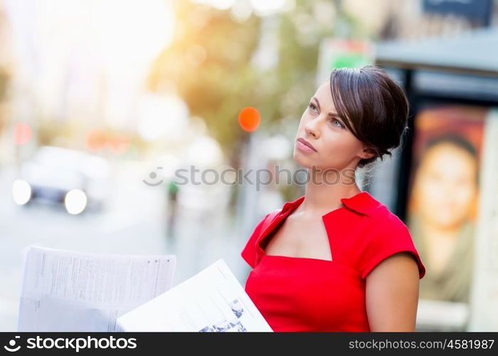 Portrait of businesswoman outside. Portrait of business woman in red dress holding papers