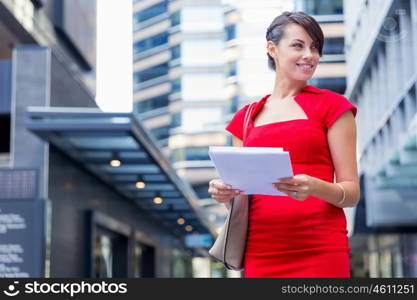 Portrait of businesswoman outside. Portrait of business woman in red dress holding papers