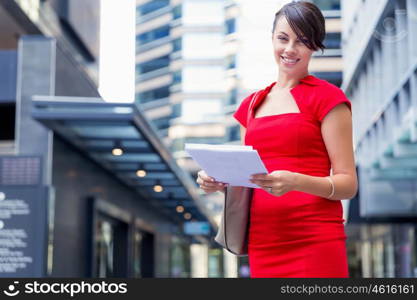 Portrait of businesswoman outside. Portrait of business woman in red dress holding papers