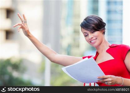 Portrait of businesswoman outside. Portrait of business woman in red dress holding papers