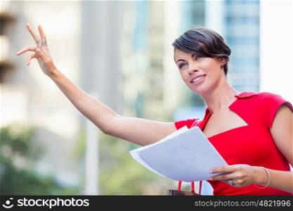 Portrait of businesswoman outside. Portrait of business woman in red dress holding papers