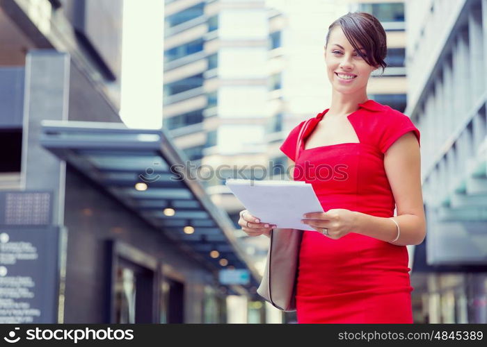 Portrait of businesswoman outside. Portrait of business woman in red dress holding papers