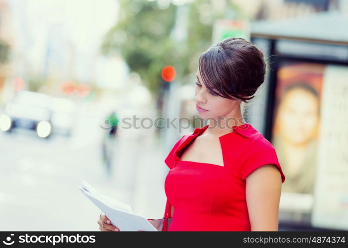 Portrait of businesswoman outside. Portrait of business woman in red dress holding papers