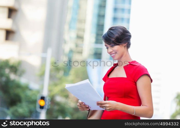 Portrait of businesswoman outside. Portrait of business woman in red dress holding papers