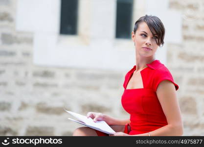 Portrait of businesswoman outside. Portrait of business woman in sitting outside and holding papers