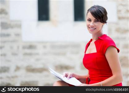 Portrait of businesswoman outside. Portrait of business woman in sitting outside and holding papers