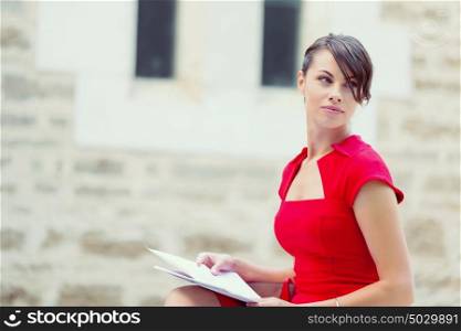 Portrait of businesswoman outside. Portrait of business woman in sitting outside and holding papers