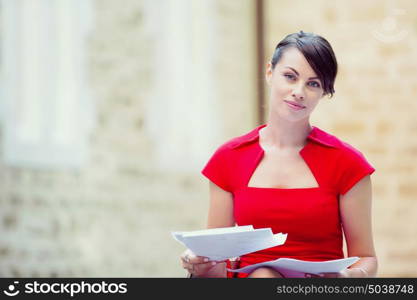 Portrait of businesswoman outside. Portrait of business woman in sitting outside and holding papers