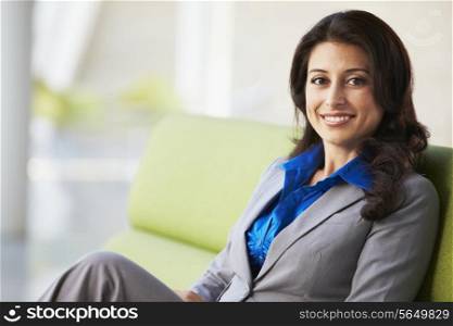 Portrait Of Businesswoman Sitting On Sofa In Modern Office