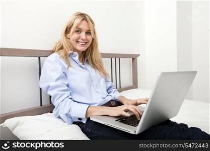Portrait of businesswoman using laptop in bed