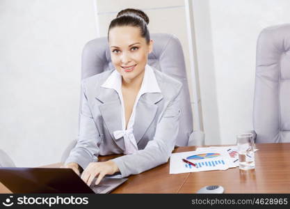 Portrait of businesswoman with laptop working at her office. Beautiful office manager