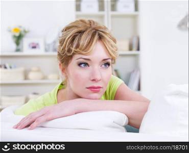 Portrait of calm young beautiful woman lying on the sofa - indoors