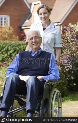 Portrait Of Carer Pushing Senior Man In Wheelchair