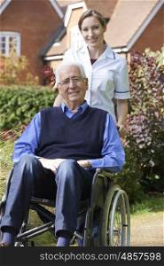 Portrait Of Carer Pushing Senior Man In Wheelchair