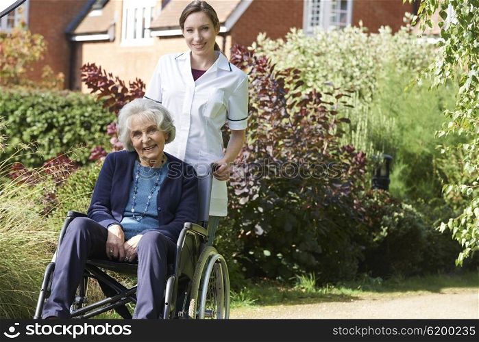 Portrait Of Carer Pushing Senior Woman In Wheelchair