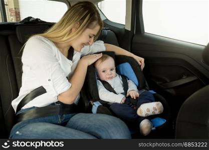 Portrait of caring mother with baby boy on car back seat