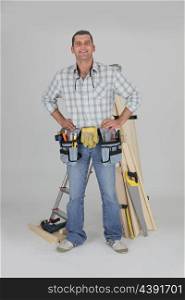 portrait of carpenter fully equipped standing with arms akimbo