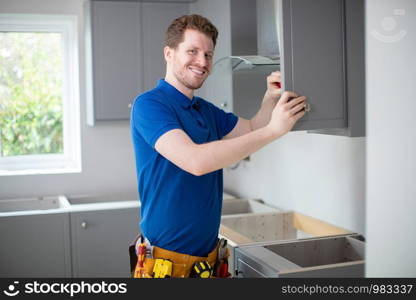 Portrait Of Carpenter Installing Luxury Modern Fitted Kitchen