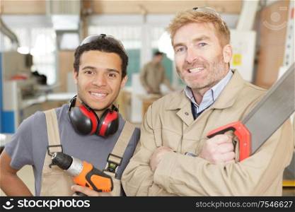portrait of carpenter with apprentice holding tools