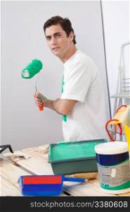 Portrait of casual man holding a roller paint brush in his hand