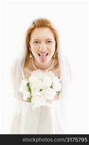 Portrait of Caucasian bride holding bouquet and sticking her tongue out