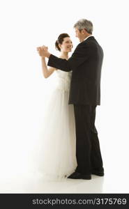 Portrait of Caucasian groom and Asian bride dancing.