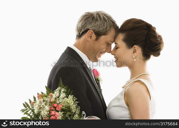 Portrait of Caucasian groom and Asian bride embracing