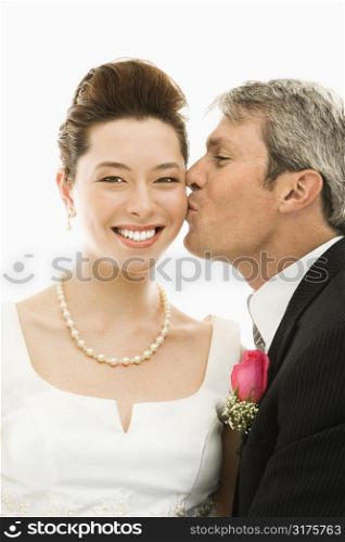 Portrait of Caucasian groom kissing Asian bride.