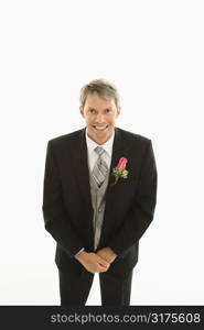 Portrait of Caucasian groom with hands clasped in front of him.