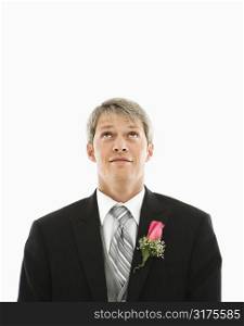 Portrait of Caucasian male in tuxedo with boutonniere looking up.