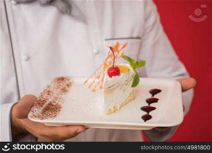Portrait of caucasian man with chef uniform sharing fresh cake. Professional serving