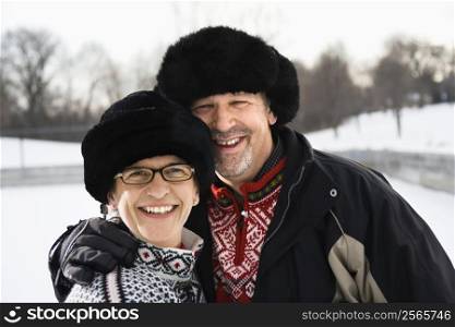 Portrait of Caucasian middle aged man and woman wearing black winter hats smiling at viewer.