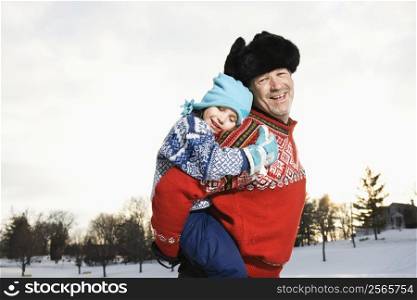 Portrait of Caucasian middle aged man holding Caucasian litte girl piggyback style smiling and looking at viewer.