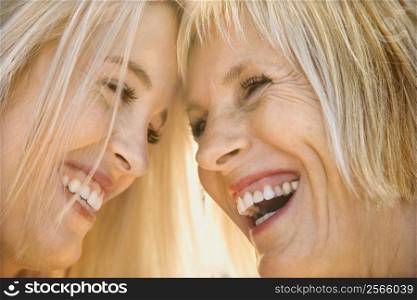 Portrait of Caucasian mother and daughter laughing and looking at each other.