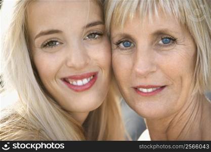 Portrait of Caucasian mother and daughter smiling looking at viewer.