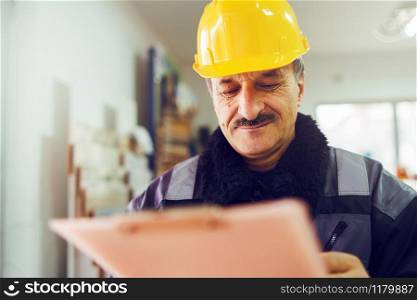 Portrait of caucasian senior man construction worker general laborer building contractor wearing yellow protective helmet holding pen and document checking data report project in the office warehouse