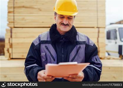 Portrait of caucasian senior man construction worker general laborer building contractor wearing yellow protective helmet holding pen and document checking data report project on the site