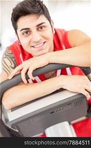 Portrait of caucasian smiling man sitting on a gym bicycle