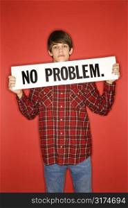 Portrait of Caucasian teen boy holding no problem sign under his chin.