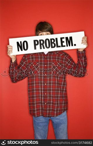 Portrait of Caucasian teen boy holding no problem sign under his eyes.
