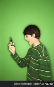 Portrait of Caucasian teen boy screaming at cellphone.